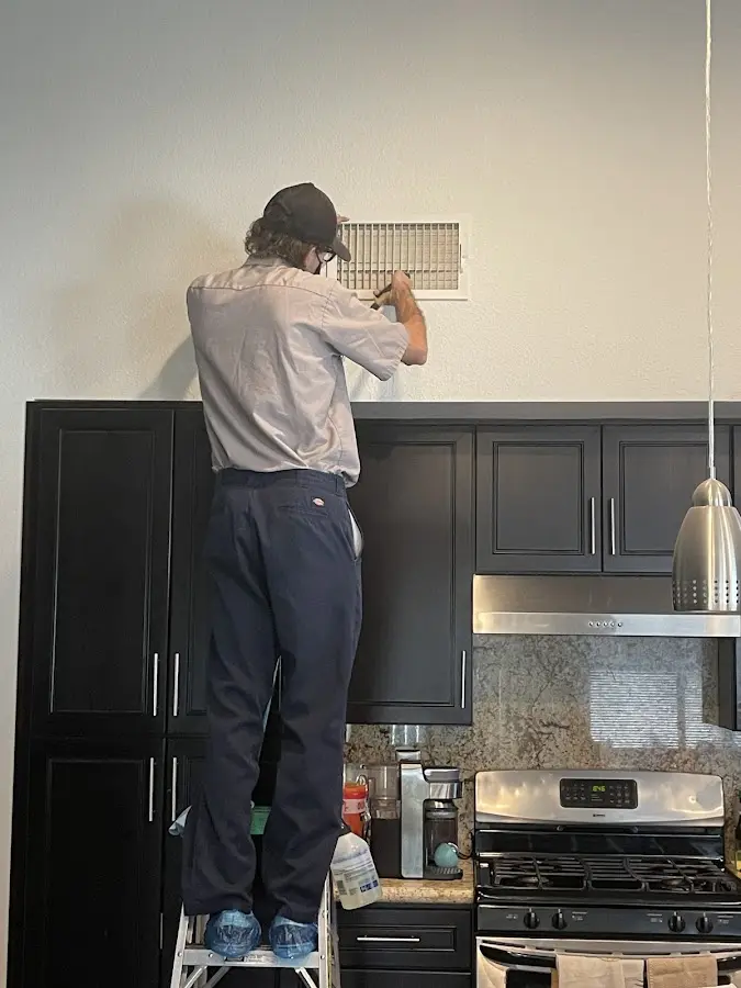 Technician inspecting an air vent during HVAC service in Cleveland Heights